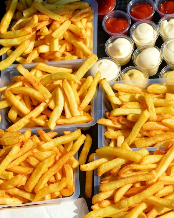 Sfeerbeeld (Unsplash): een plank met friet en sausjes